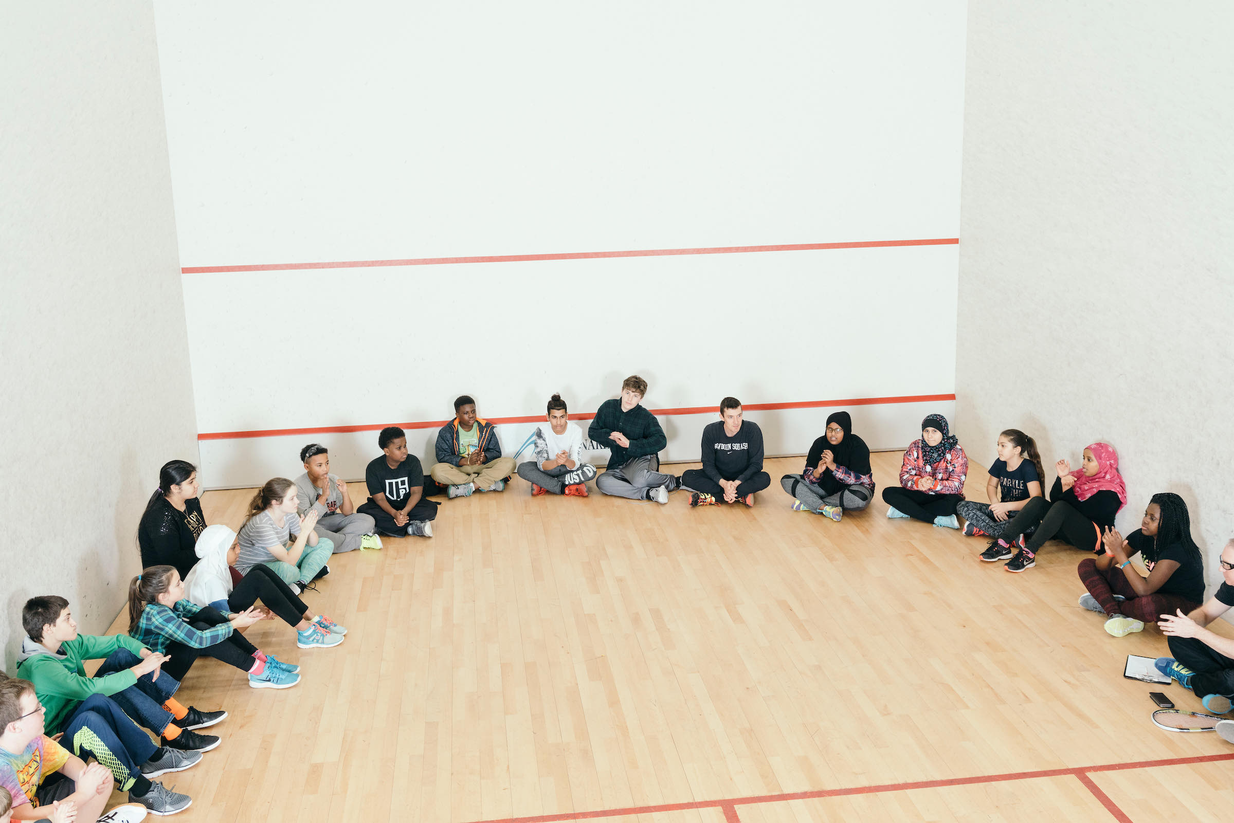 Barrett Takesian, center, Bowdoin College alum (Class of 2012) and Executive Director of Portland Community Squash in Portland, Maine, wraps up a coaching session with kids on Wednesday, Jan. 10, 2018. Portland Community Squash offers youth from a diverse socio-economic and ethnic backgrounds after school opportunities to learn squash, benefit from academic tutoring and improve their overall physical and intellectual wellness.